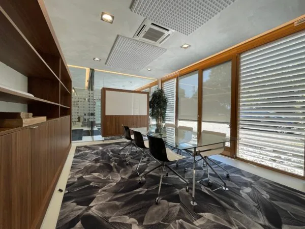 Moderne vergaderruimte aan de Charloisse Lagedijk met glazen tafel, houten inrichting en opvallend zwart-wit bladpatroon op het tapijt.